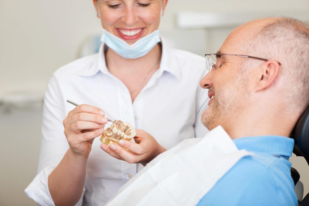 dentist showing patient a sample of Transitional dentures naples